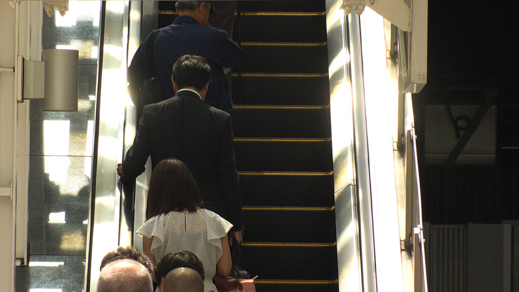 Back shot of people on escalator, Shinjuku, Tokyo, Japan.